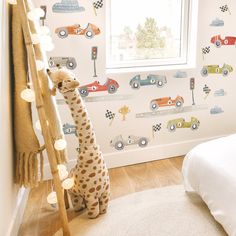 a child's bedroom with a giraffe and cars on the wall