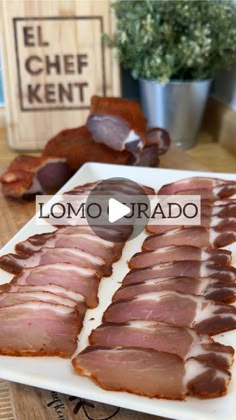 sliced ham on a white plate sitting on a wooden table next to other food items