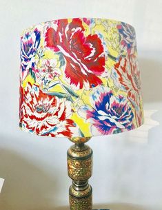 a lamp that is sitting on top of a table with a flower print lampshade