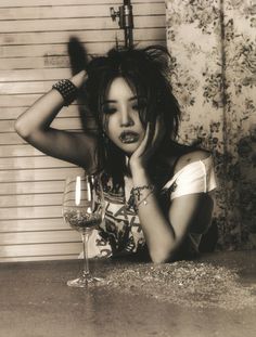 a woman sitting at a table with a glass of wine in front of her face