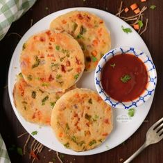 some food is sitting on a plate next to a fork and sauce in a bowl