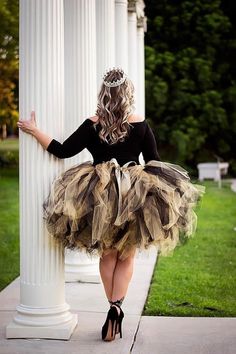 a woman in a tutu is leaning against a pillar