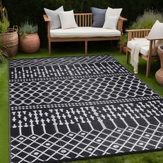 a black and white rug sitting on top of a grass covered field next to wooden benches