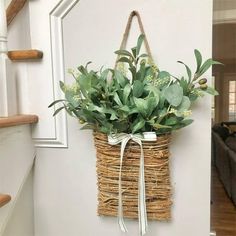 a basket hanging on the wall with greenery in it