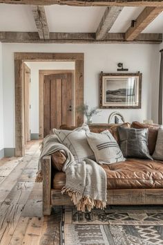 a living room filled with lots of furniture and wooden beams on the ceiling, along with a leather couch