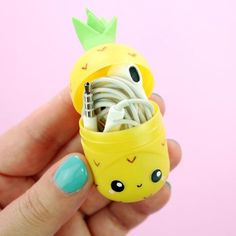 a hand holding a small yellow pineapple cell phone charger in it's holder