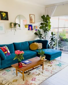 a living room with blue couches and potted plants on the table in front of a large window