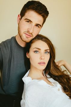 a man standing next to a woman with long brown hair and blue eyeliners