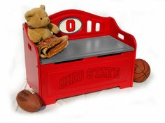 a teddy bear sitting on top of a red toy bench with baseballs and ball