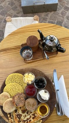 a wooden plate topped with different types of food on top of a table next to a tea pot