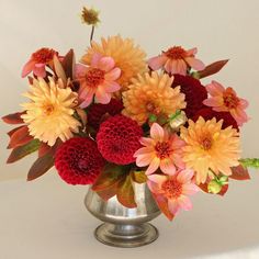 a silver vase filled with red and yellow flowers