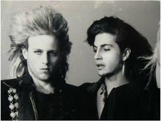 three men standing next to each other in front of a wall with long blonde hair