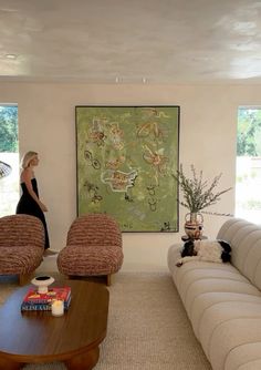 a woman is standing in the living room with two couches and a coffee table