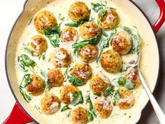 a pan filled with meatballs and spinach on top of a table next to a spoon