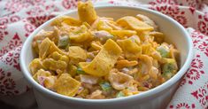 a white bowl filled with cheesy pasta salad on top of a red and white cloth