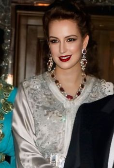 a woman in a white dress and red lipstick standing next to a man wearing a tuxedo