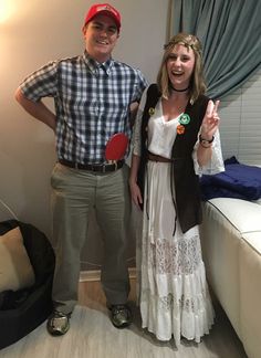 a man and woman standing next to each other in front of a bed with a ping pong paddle on it