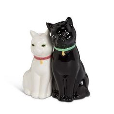 two black and white ceramic cats sitting next to each other on a white background,