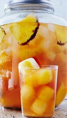 a pitcher and glass filled with liquid sitting on top of a wooden table next to each other