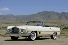 an old white car parked in the desert