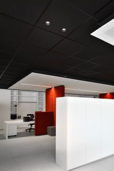 an empty office with white walls and red accenting the space between two desks