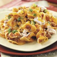 a white plate topped with pasta covered in cheese and meat sauce on top of a red place mat