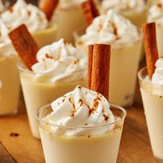 there are many desserts with cinnamon sticks in the cups on the table, and one is topped with whipped cream