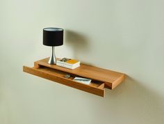 a wooden shelf with a lamp and books on it next to a wall mounted clock