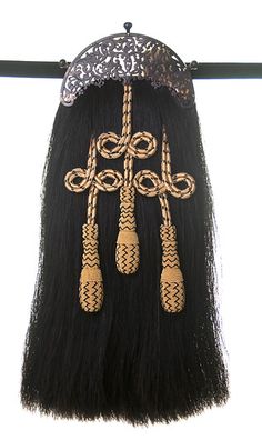 a long black wig with gold and silver decorations hanging from it's back end