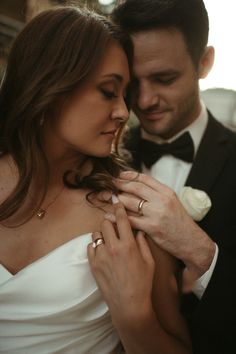 a man in a tuxedo and a woman in a wedding dress hold their hands close together