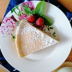 a piece of cheesecake on a plate with strawberries and mint sprigs