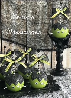 some green and black decorated eggs on a table with ribbon around the eyes, bows and ears