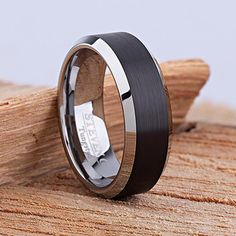 a black and white wedding ring on top of a piece of wood with the word love written