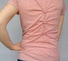 a woman with her back to the camera and holding her hands on her hips while wearing a pink t - shirt