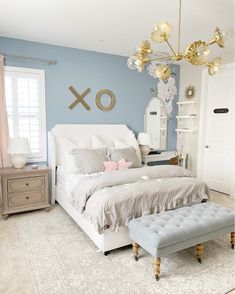 a bedroom with blue walls and white bedding has a bench in front of the bed