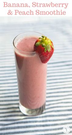 a banana, strawberry and peach smoothie in a glass on a striped tablecloth