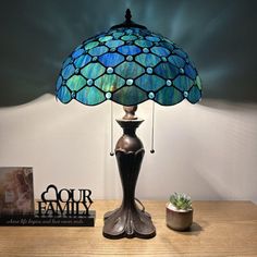 a lamp that is sitting on top of a table next to a book and potted plant