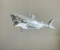 a silver fish ornament hanging from a string in the shape of a shark