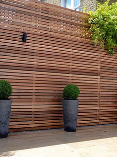 three black planters sitting next to a wooden fence