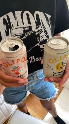 two people are holding cans of beer in their hands