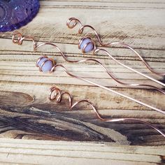 three pieces of copper wire sitting on top of a wooden table