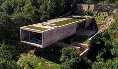 an aerial view of a house in the middle of some trees and grass on top of it