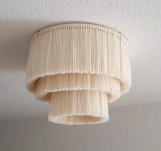 a lamp shade hanging from the ceiling in a room with white walls and carpeting