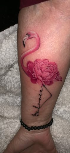 a flamingo tattoo on the leg with a pink flower and name written in it