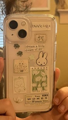 a person holding up a phone case with stickers on it