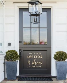 the front door is decorated with two planters and a welcome sign