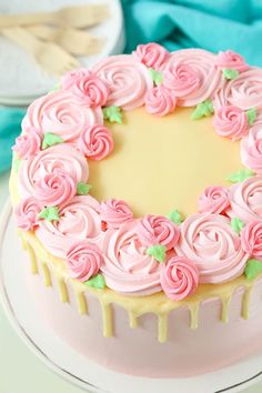 a cake with pink frosting and roses on top is sitting on a white plate