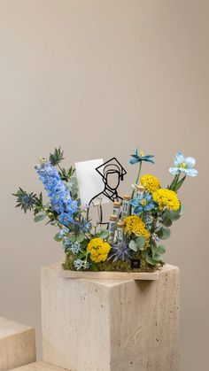 an arrangement of flowers and plants in a vase on top of a stone block,