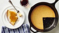 a skillet with a piece of pie on it next to a plate and cup