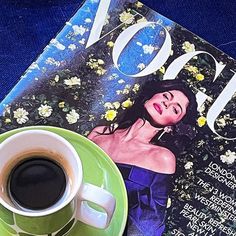 a cup of coffee sitting on top of a green saucer next to a magazine